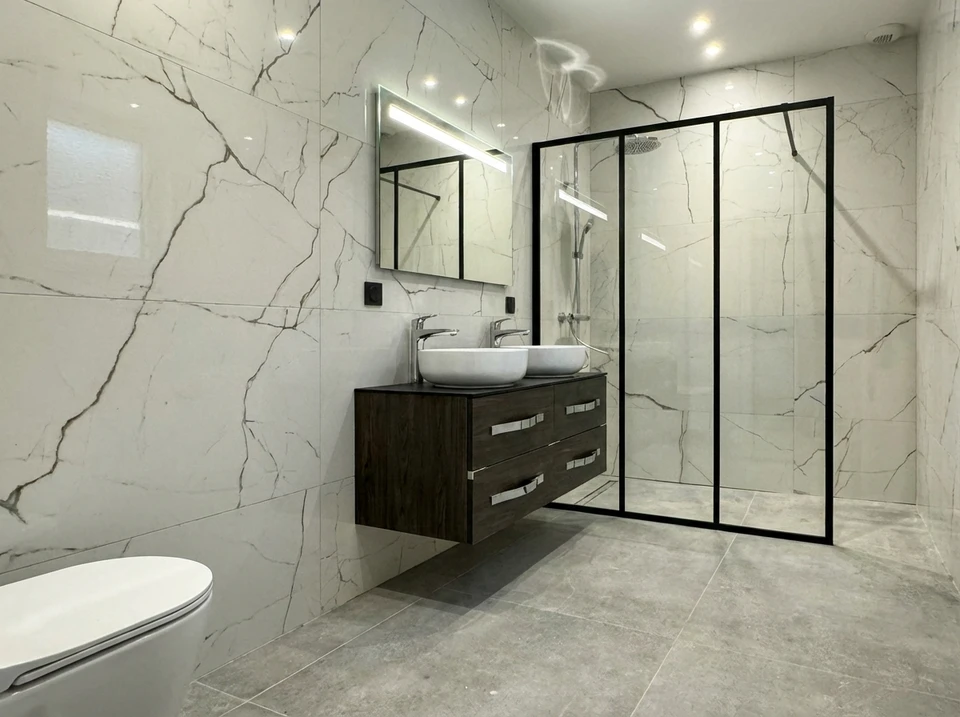 Un homme en v&ecirc;tement de travail blanc avec logo vert installe une pomme de douche dans une cabine de douche moderne