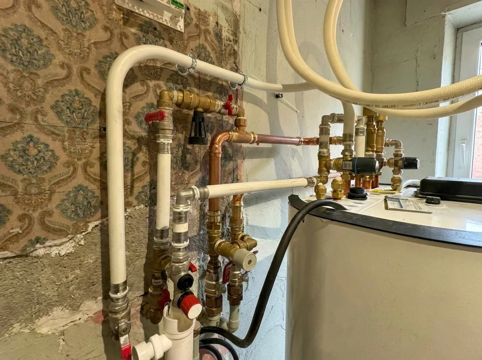 Cuisine moderne avec chaudière murale blanche installée dans un placard ouvert, entourée de meubles blancs contemporains