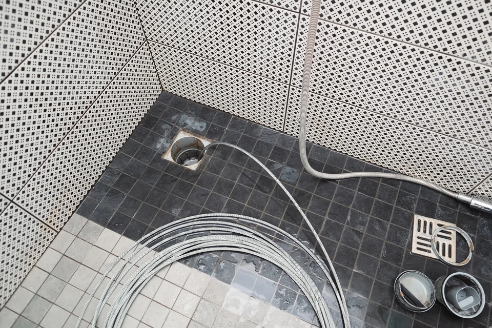 plombier débloquant le drain de douche bloqué avec jet d'eau à la salle de bains à la maison