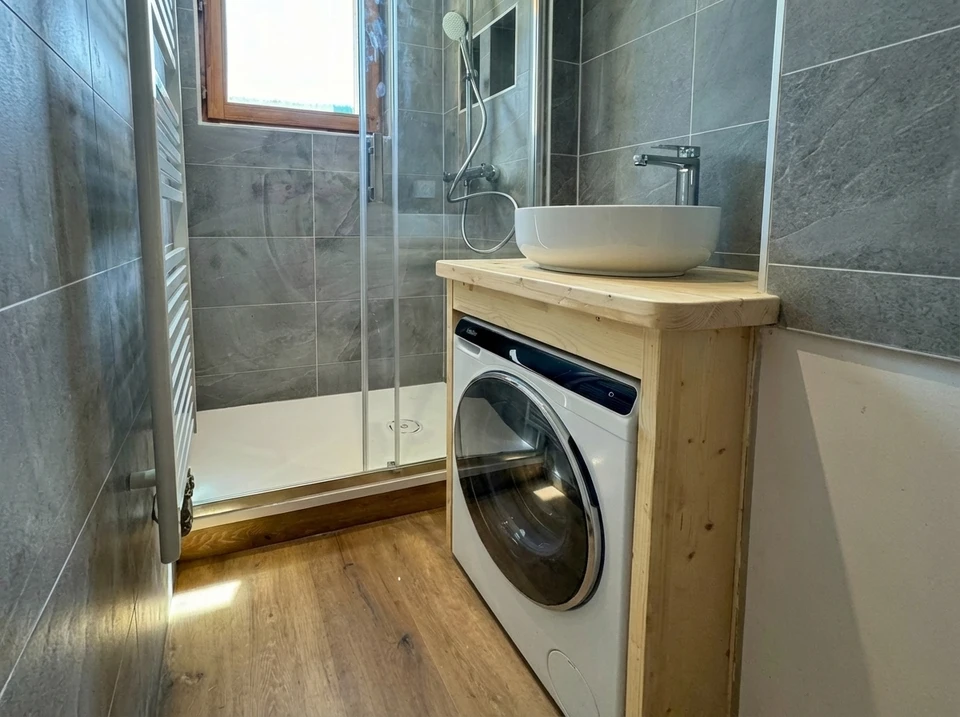 Un plombier en veste rouge utilise un chalumeau à gaz pour souder une canalisation en cuivre dans un environnement intérieur