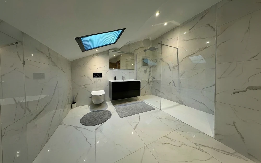 Salle de bain moderne avec douche à l'italienne en verre transparent, receveur blanc, colonne de douche chromée
