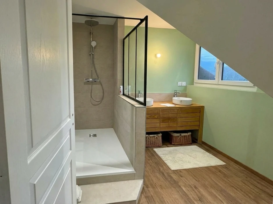 Salle de bain compacte avec douche à l'italienne en verre, vasque à poser ronde sur meuble en bois massif brut intégrant un lave-linge frontal blanc Candy