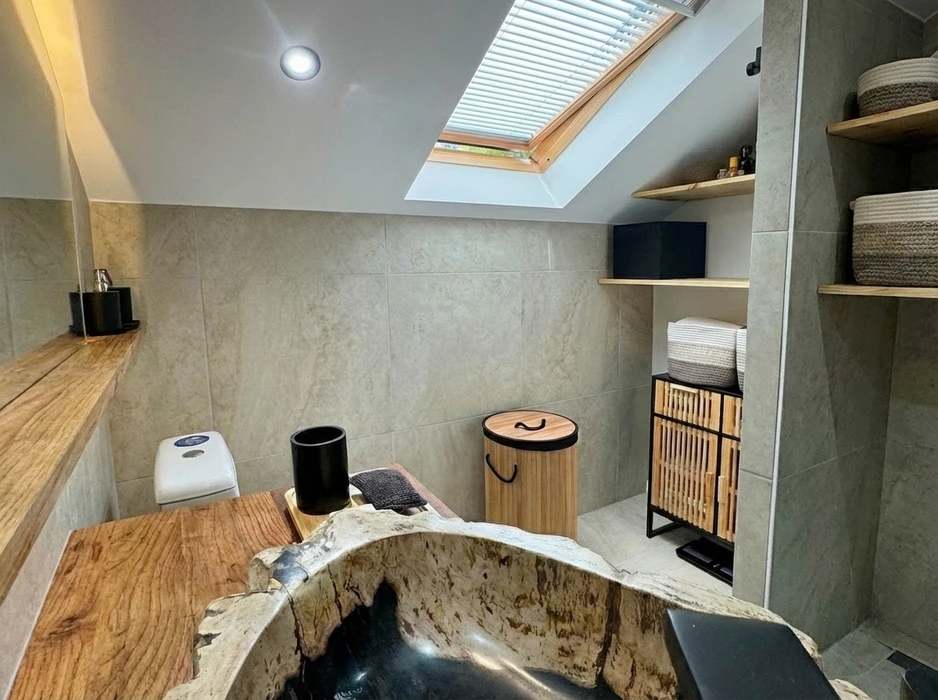 Salle de bain compacte avec douche à l'italienne en verre, vasque à poser ronde sur meuble en bois massif brut intégrant un lave-linge frontal blanc Candy