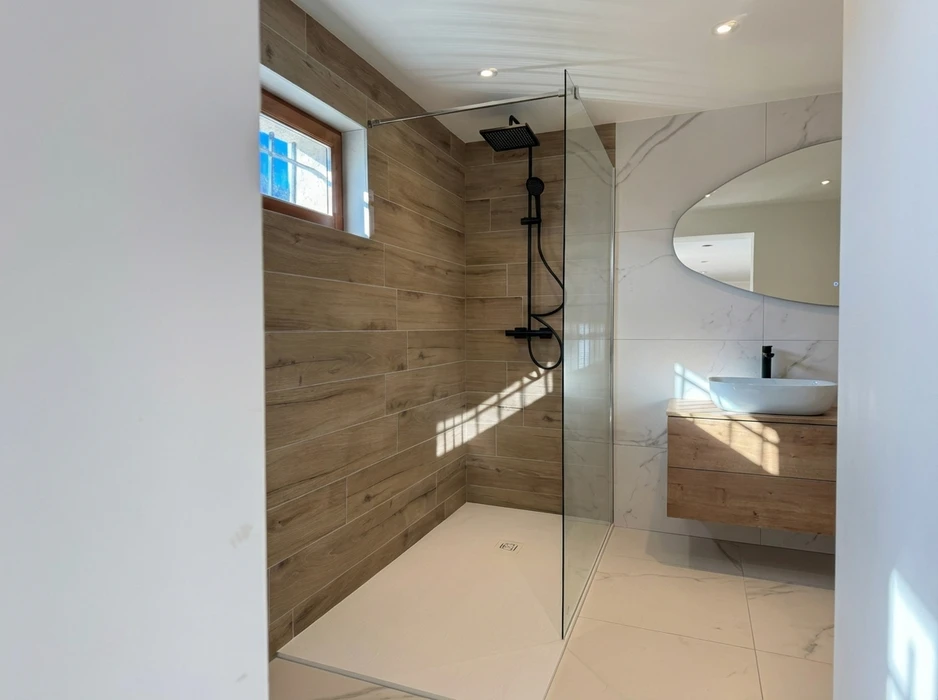 Salle de bain compacte avec douche à l'italienne en verre, vasque à poser ronde sur meuble en bois massif brut intégrant un lave-linge frontal blanc Candy