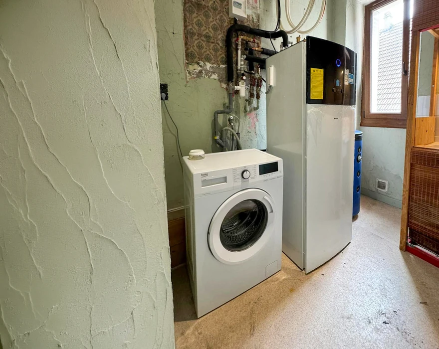 Salle de bain compacte avec douche à l'italienne en verre, vasque à poser ronde sur meuble en bois massif brut intégrant un lave-linge frontal blanc Candy