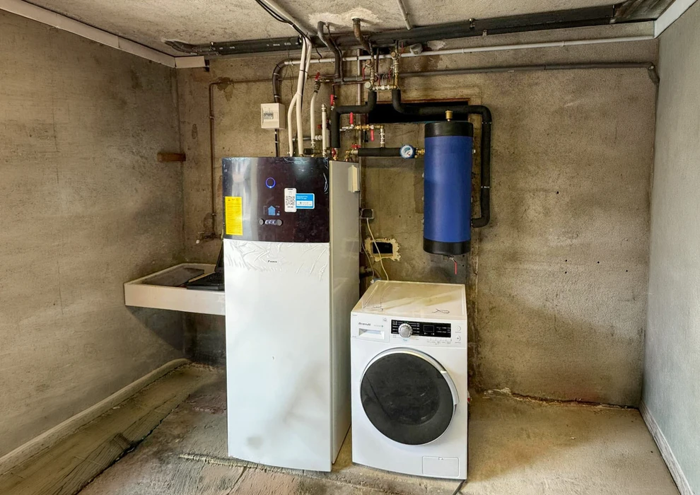 Salle de bain compacte avec douche à l'italienne en verre, vasque à poser ronde sur meuble en bois massif brut intégrant un lave-linge frontal blanc Candy
